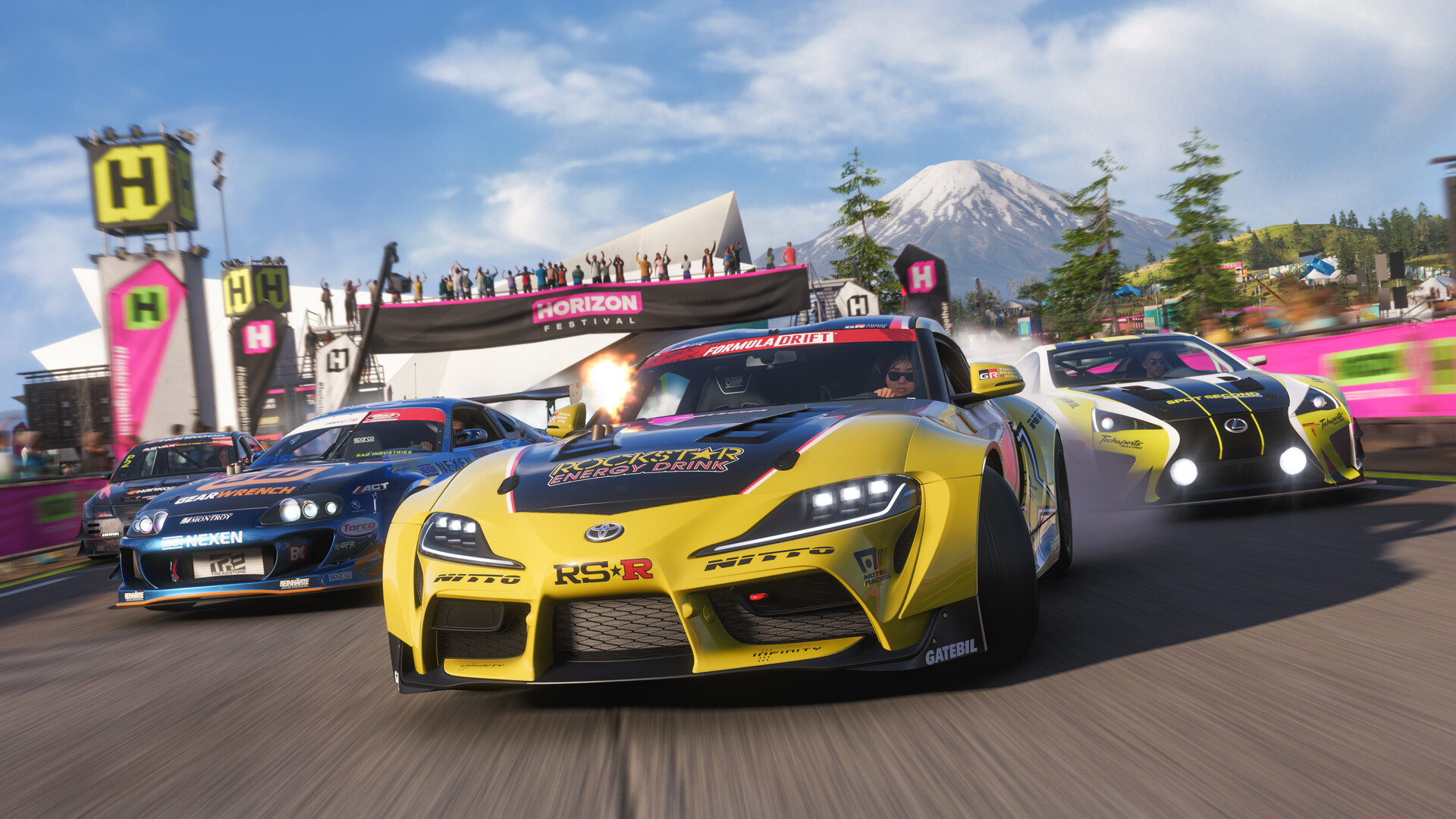 Three sports cars racing beneath a mountain backdrop