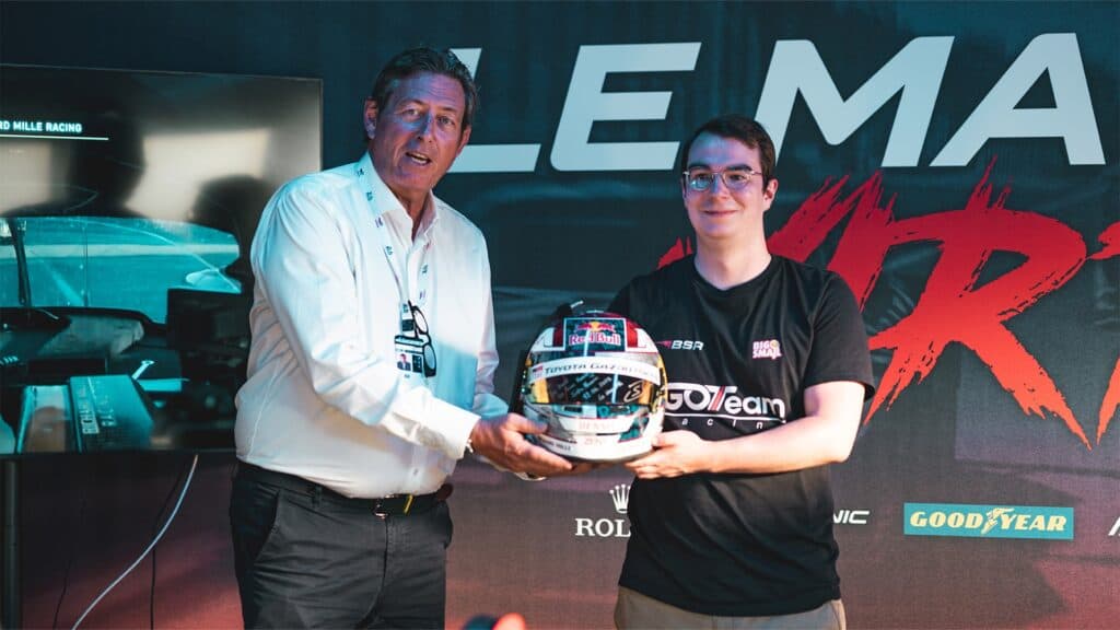 Gérard Neveu presents Rémi Delorme with Buemi's helmet at the Le Mans Virtual Challenge